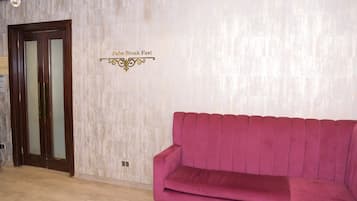 A reception area with a wooden door and a sign that reads "Palm Break Fast." A pink sofa is positioned in front of the door.