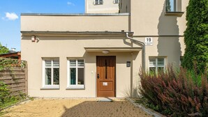 A building with a number 19 sign, a wooden door, and a paved entrance area. - Haffnera 19 - Sea & City Moments by Lion Apartments Sopot (Sopot)
