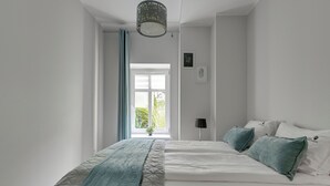 A bedroom with a bed, a window, a wall-mounted lamp, and a ceiling light fixture. - Haffnera 19 - Sea & City Moments by Lion Apartments Sopot (Sopot)