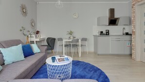 A modern living room with a grey sofa, a round coffee table, and a dining area with a white table and chairs. - Haffnera 19 - Sea & City Moments by Lion Apartments Sopot (Sopot)