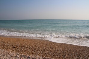 Una playa de guijarros con olas suaves que acarician la orilla.