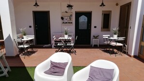A covered patio area with two white chairs, a small table, and potted plants. - B&b Sogni d'Oro (Civitanova Marche)