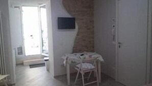 A room with a door, a small table with a chair, and a wall-mounted television. - B&b Sogni d'Oro (Civitanova Marche)