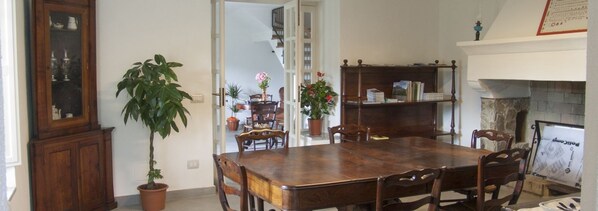 Comedor con mesa y sillas de madera, un armario y plantas en macetas.