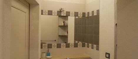 Un baño con lavamanos, espejo y paredes de azulejos.