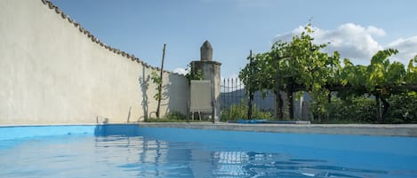 Una piscina al aire libre de temporada, sombrillas