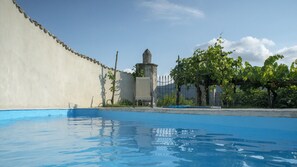 A swimming pool with a stone wall and a chair near a fence. - Il Casino di Donna Maria (Mormanno)