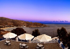 Relax in a shaded seating area overlooking the water, surrounded by a low railing and stone tiles.
