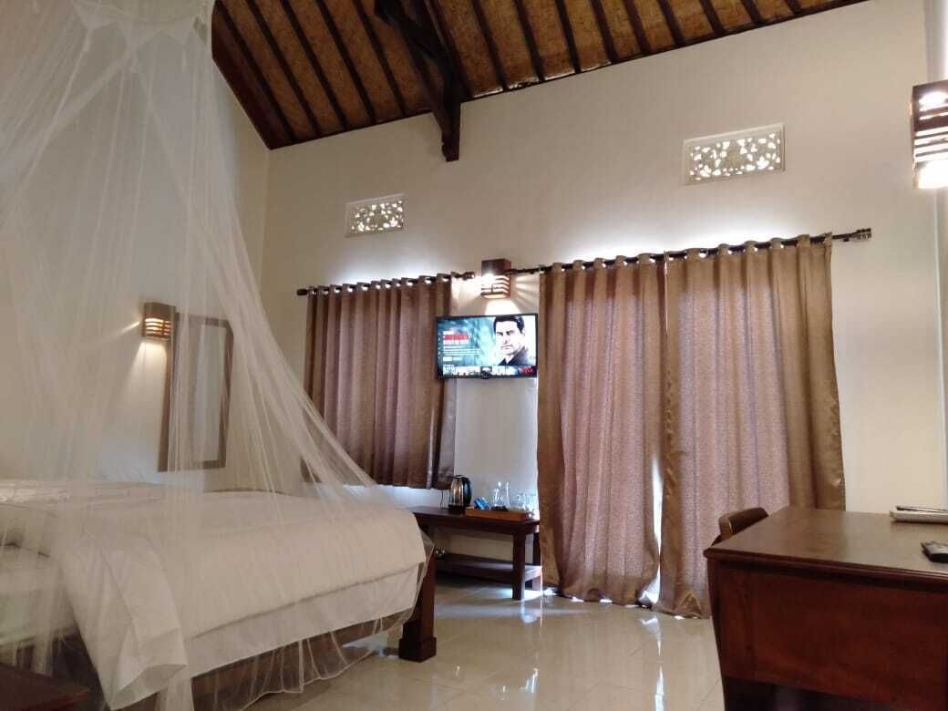A bedroom with a bed, curtains, a TV, and a desk.