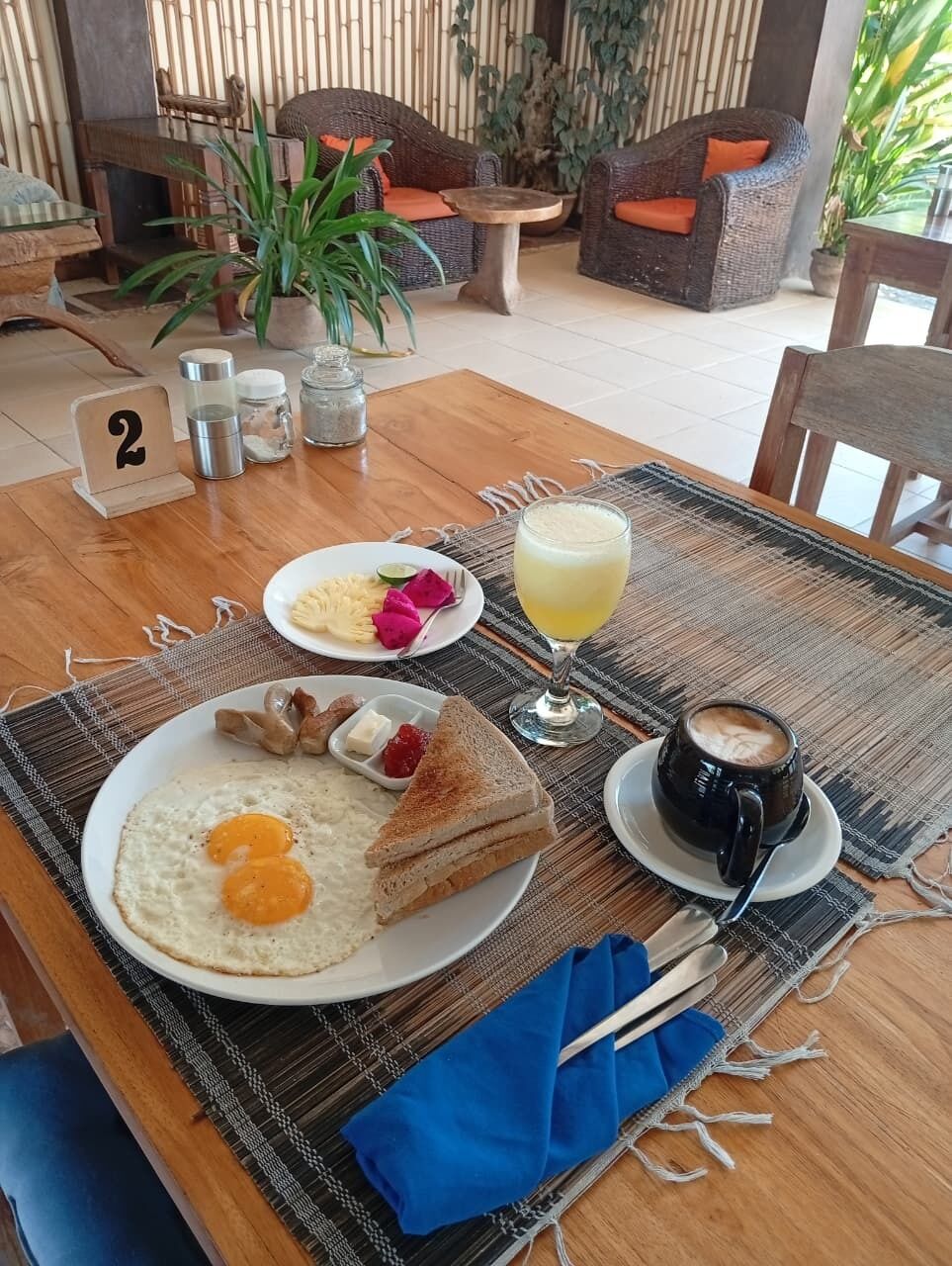 Un desayuno con una mesa, platos de comida, un vaso de jugo y una taza de café.
