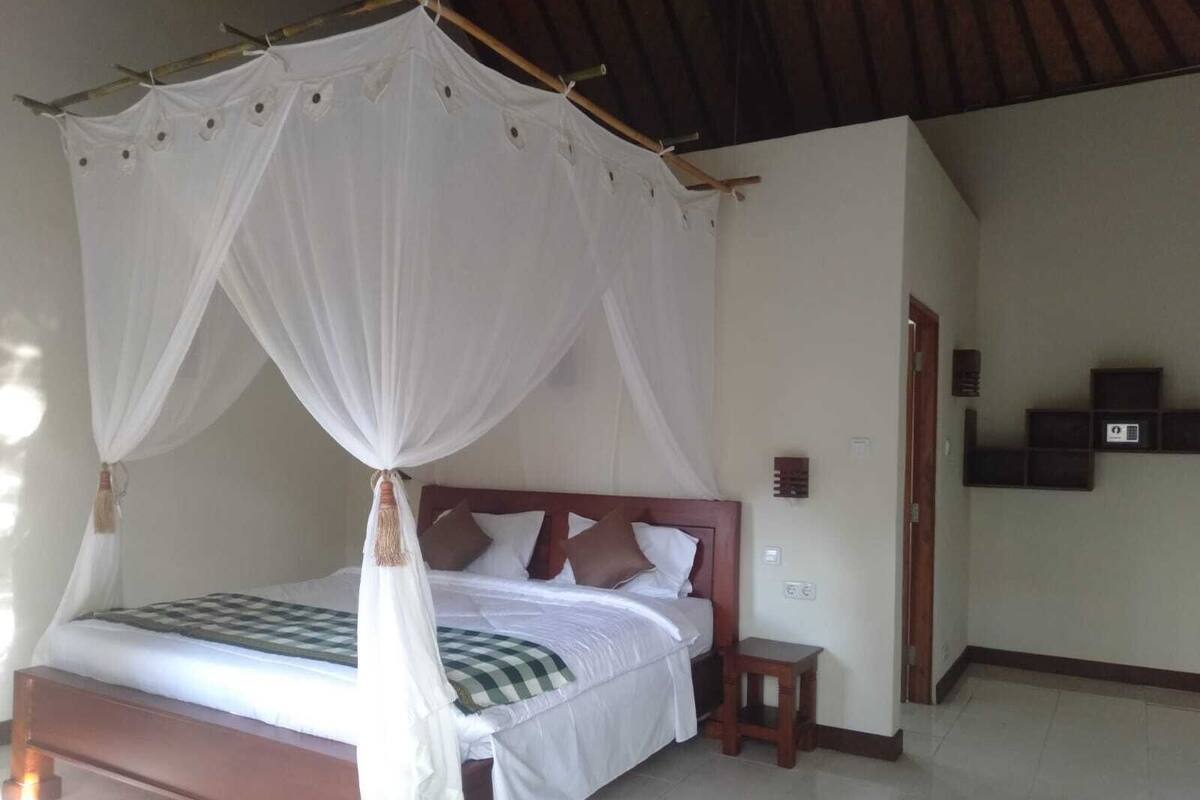 Ein Bett mit Baldachin, einem Holzkopfstück und einer karierten Tagesdecke.