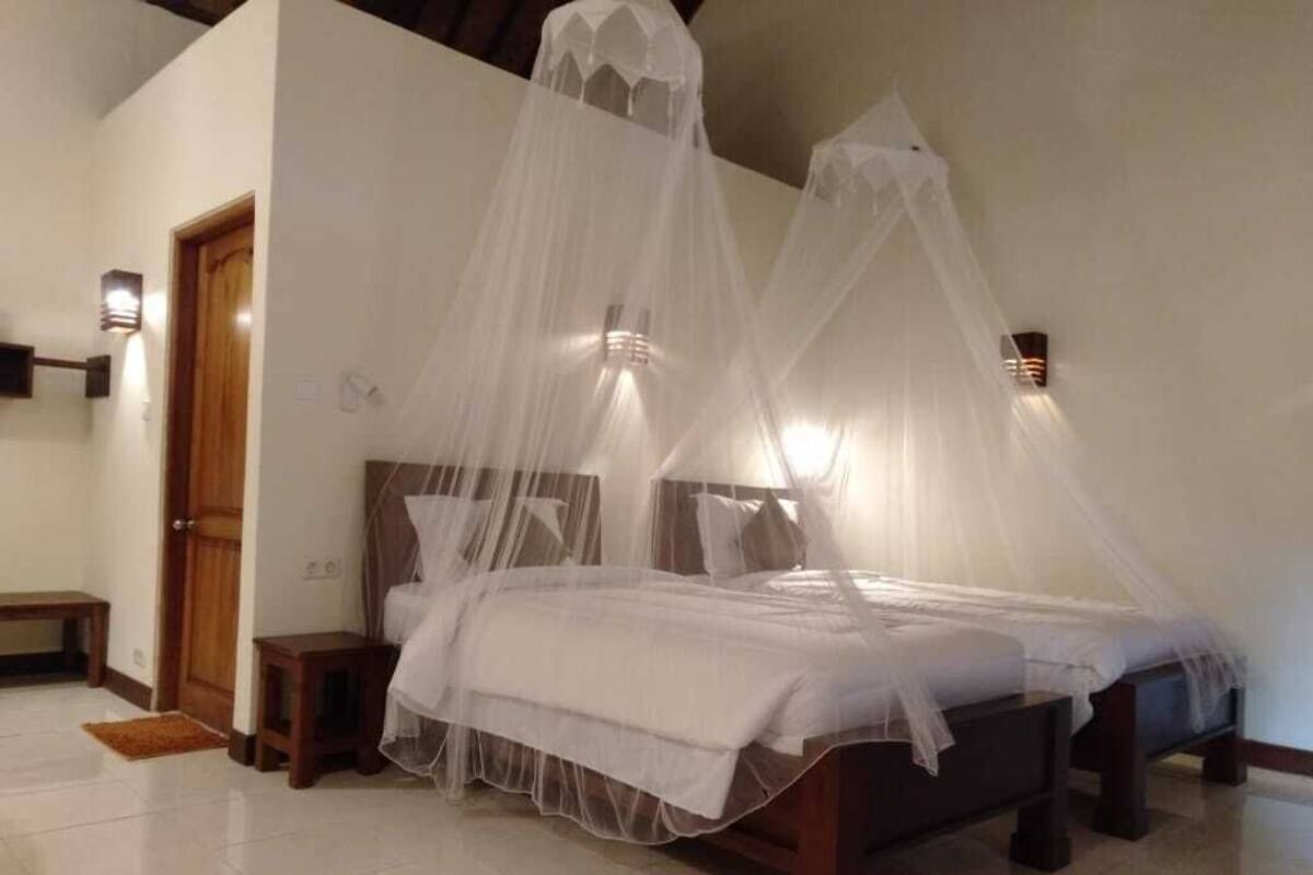 Ein Schlafzimmer mit einem Bett, das mit einem weißen Baldachin versehen ist, zwei Nachttischen und Wandleuchten.
