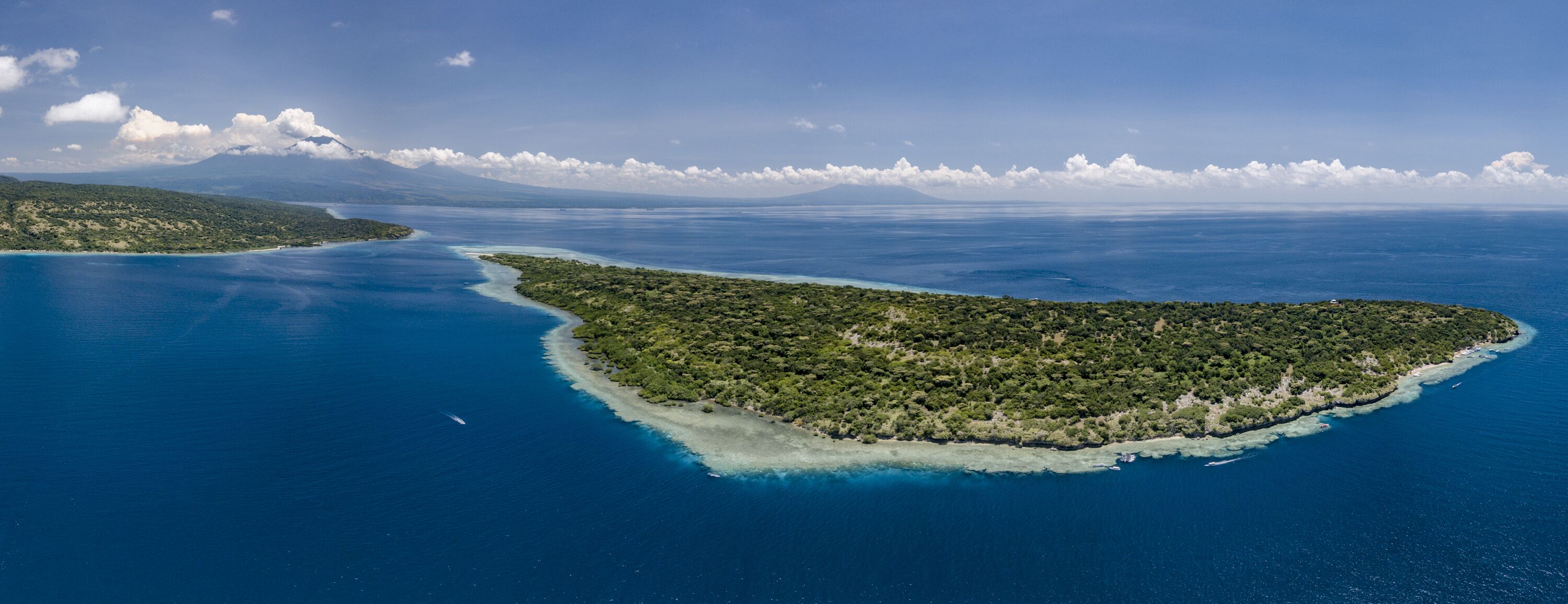 An aerial view of a lush, green island surrounded by clear blue waters.