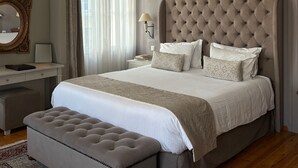 A bedroom with a large bed, a bedside table, a lamp, a mirror, and a hanging light fixture. - Capsis Bristol Boutique Hotel (Thessaloniki)