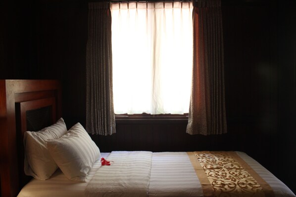 A hotel room with a bed, a window with curtains, and a headboard. - Puri Komodo Resort (Labuan Bajo)