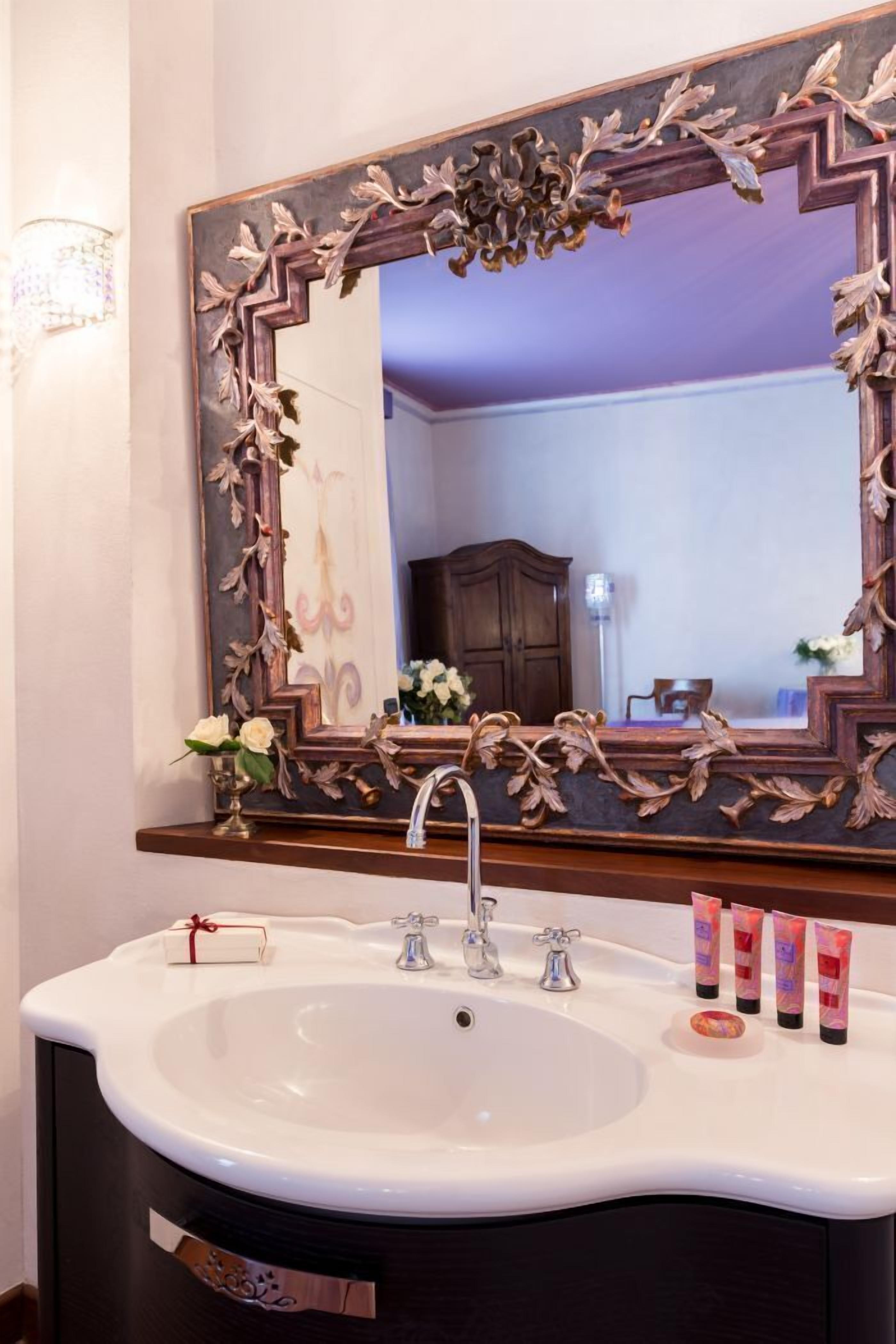 A bathroom with a large mirror, a white sink, and toiletries.