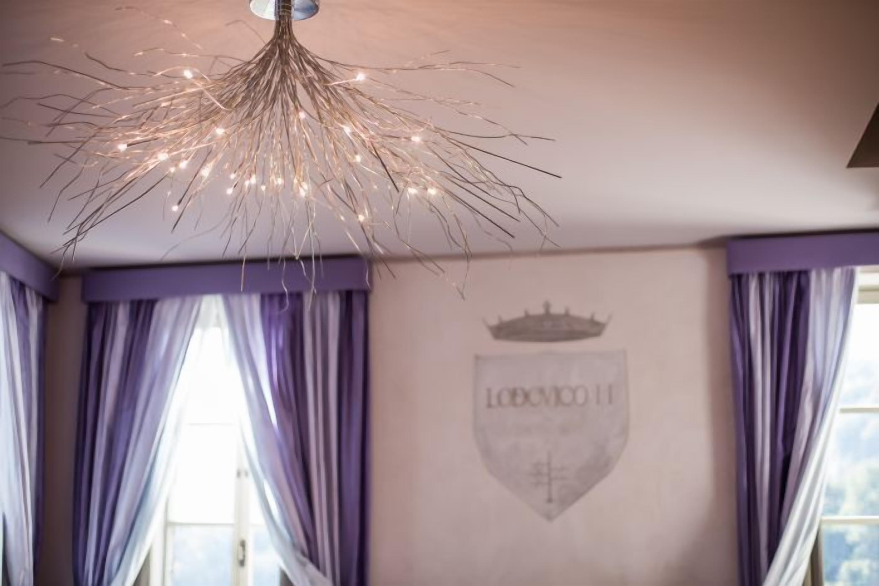 A room with a chandelier, purple curtains, and a shield emblem on the wall.
