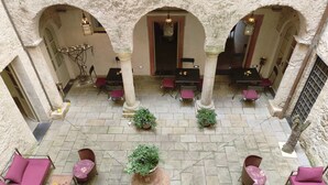 Un amplio patio con suelo de piedra, varias zonas de estar y un arreglo central de plantas.