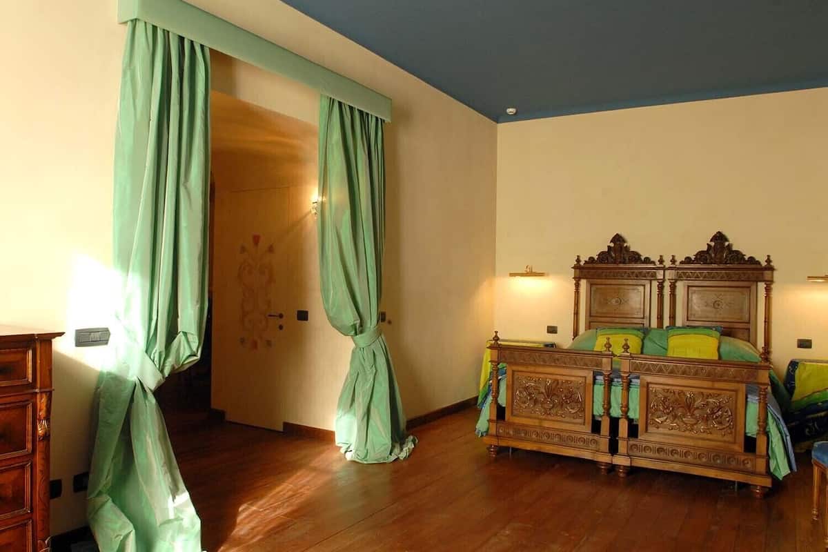 Un dormitorio con cama de madera, cortinas verdes y un armario de madera.