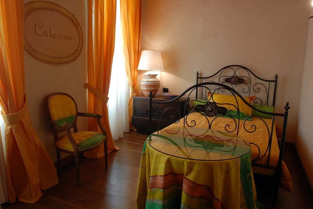 Un dormitorio con cama, una silla, una mesita de noche y una lámpara.