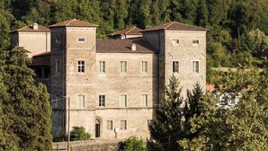 Un edificio de piedra con varias ventanas y techo de tejas, rodeado de árboles.