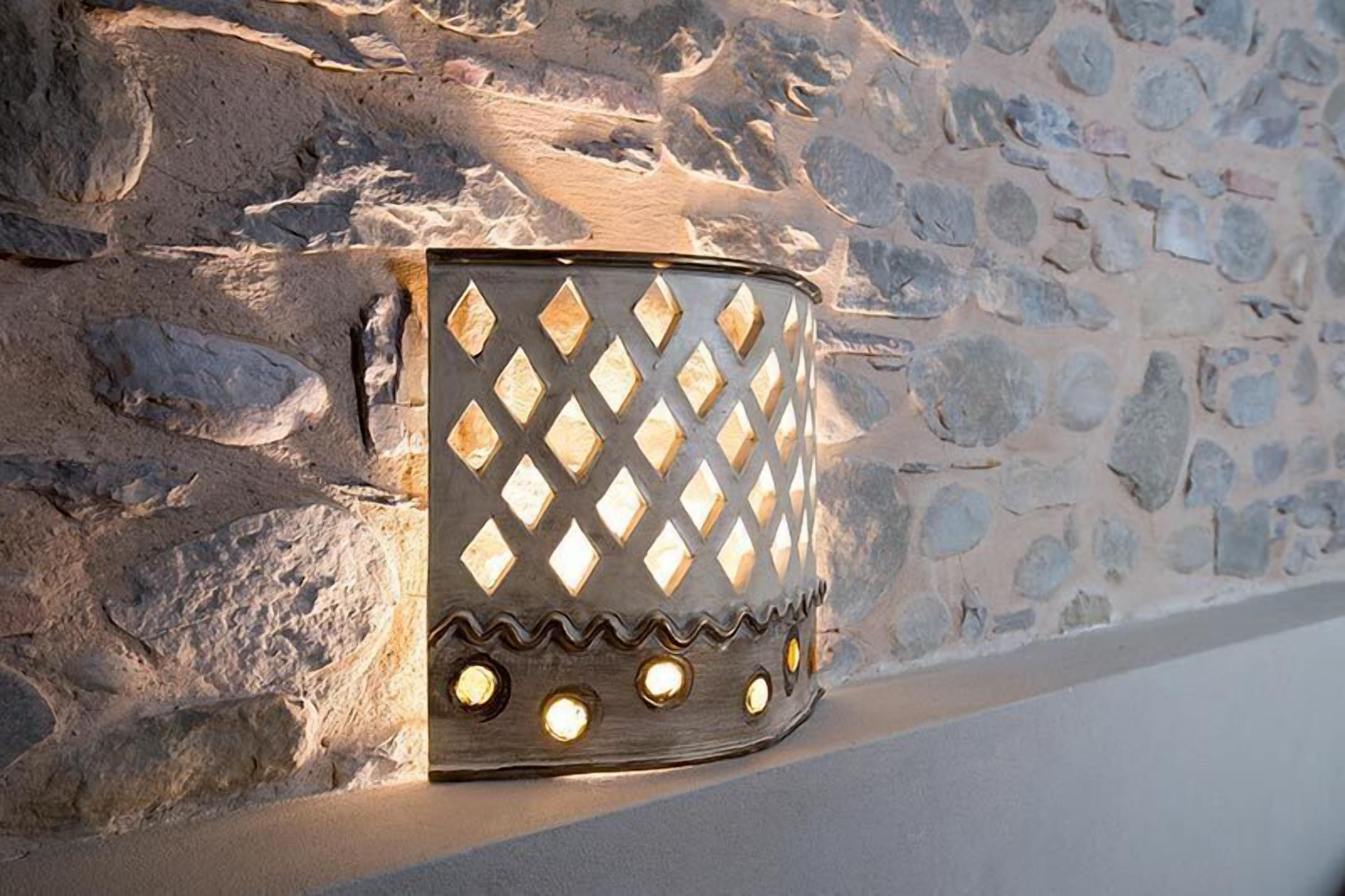 Een wandlamp met een diamantpatroon, geplaatst tegen een stenen muur.