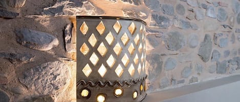 Een wandlamp met een diamantpatroon, geplaatst tegen een stenen muur.