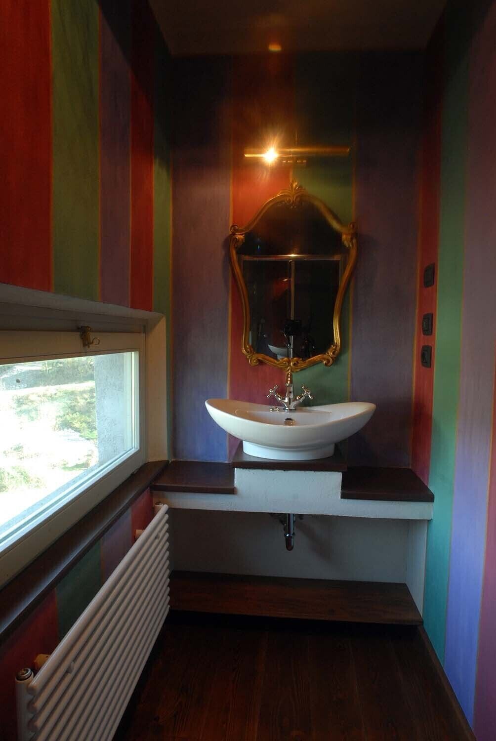 A bathroom with a white sink, a mirror, and a window.