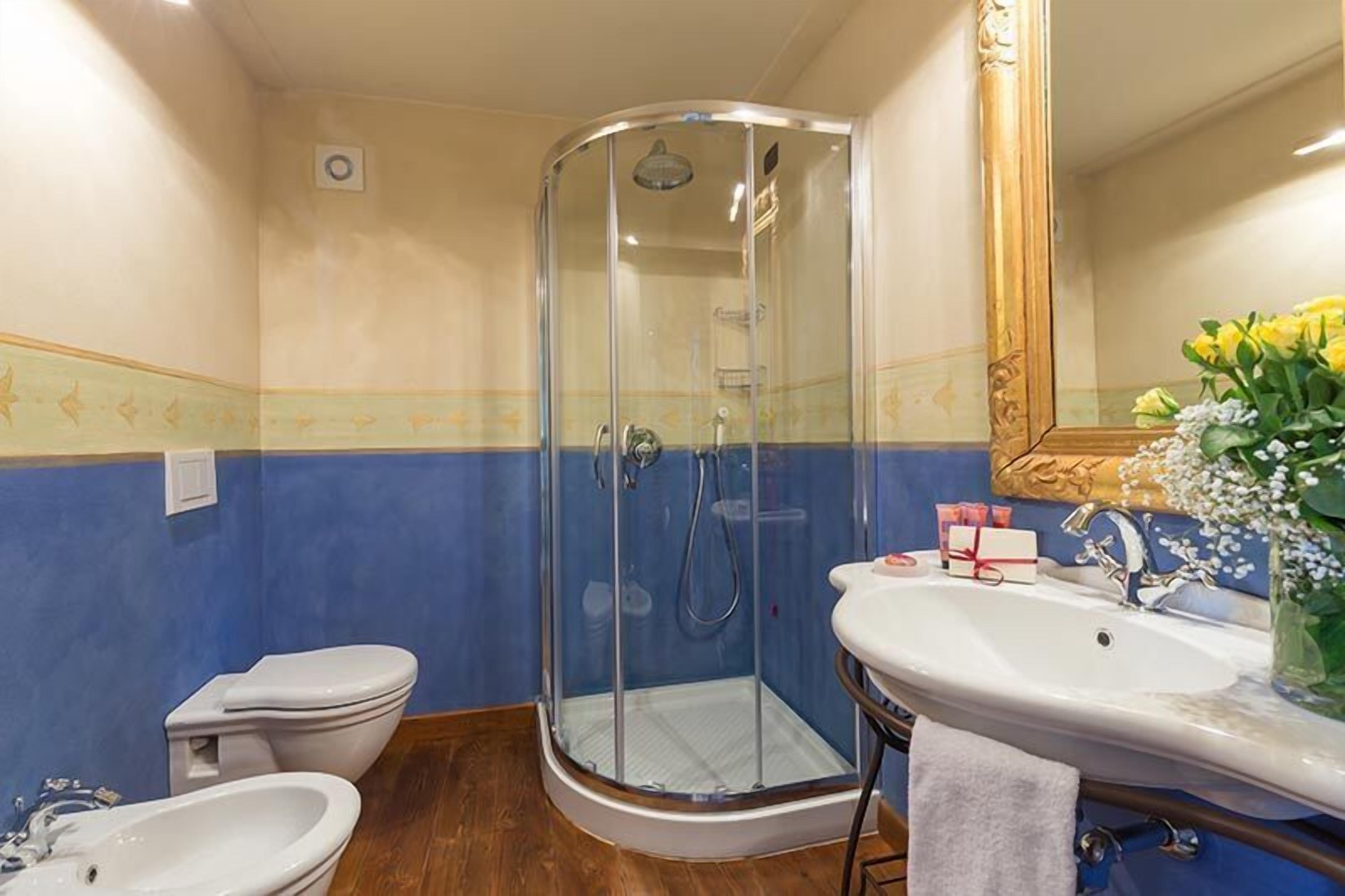 A bathroom with a glass-enclosed shower, a white sink, and a toilet.