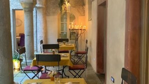 Un comedor interior con mesas dispuestas para dos, con manteles amarillos y sillas rojas.