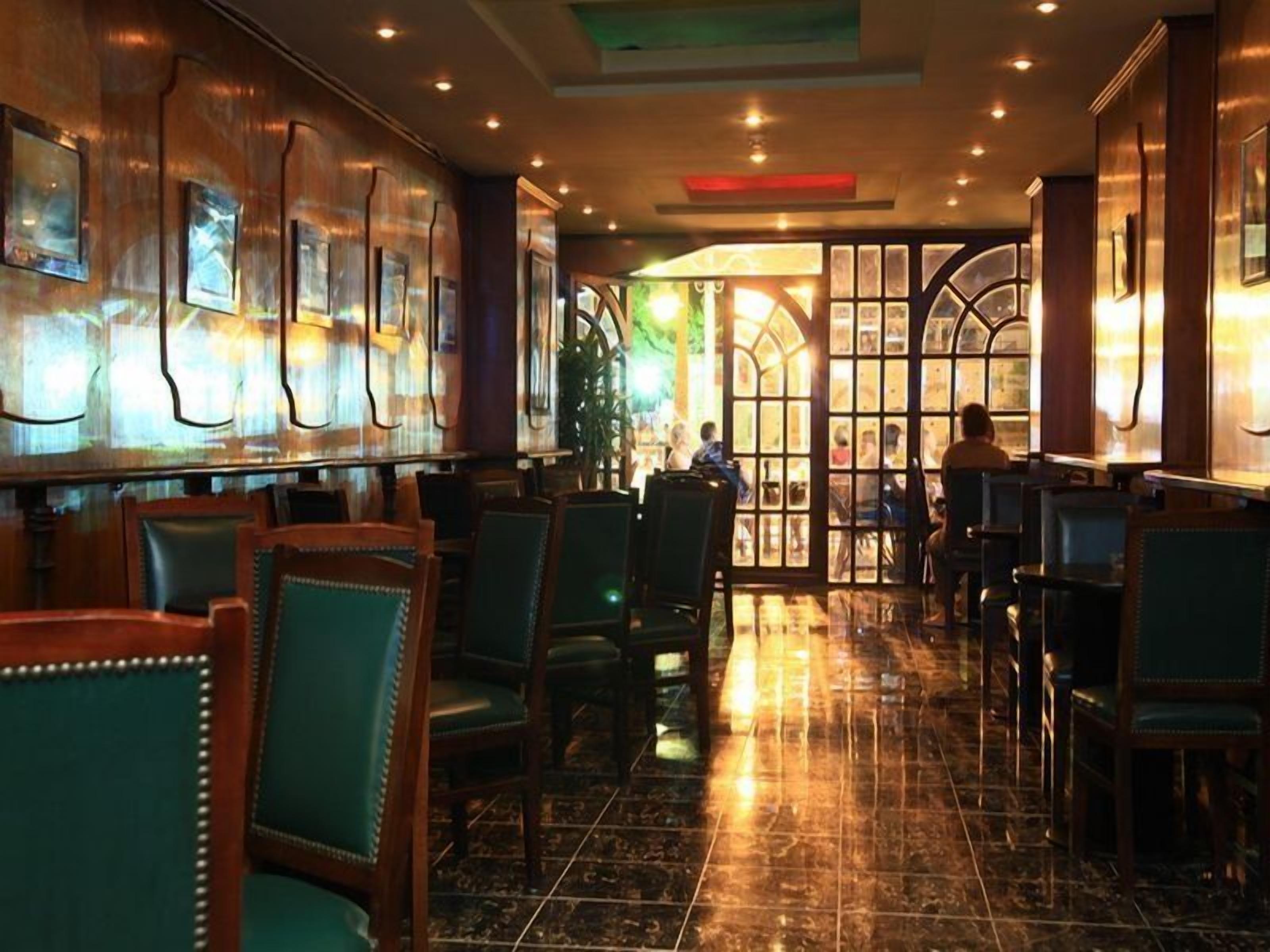 A restaurant interior with a bar area, seating, and a view through a glass door.