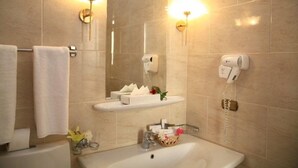 A bathroom with a sink, towel rack, and two wall-mounted hair dryers.