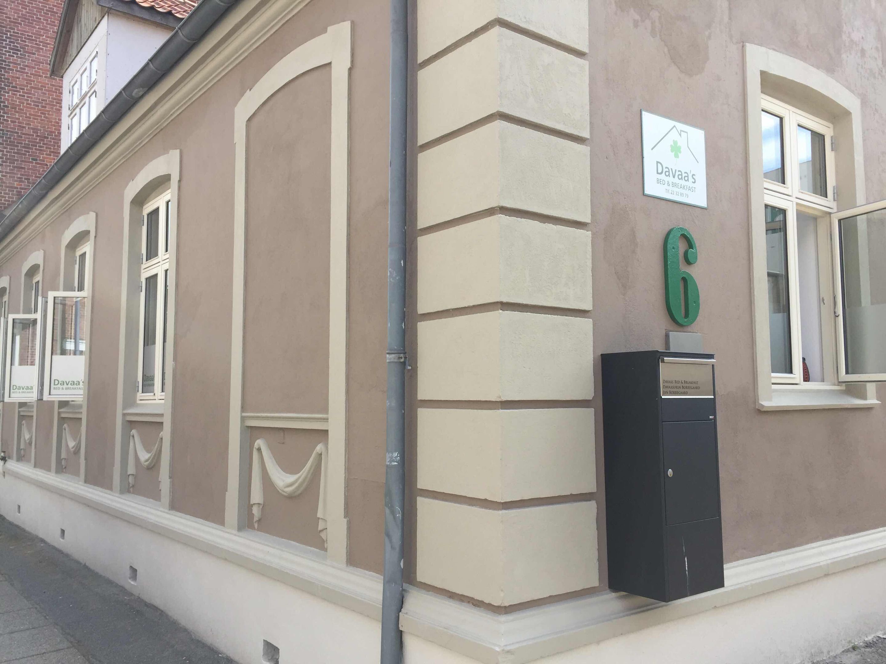 A building with a beige facade, a sign for 'Dava's Bed & Breakfast', and a mailbox with a green number '6'.
