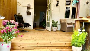 A wooden deck with a chair and potted plants. - Davaa’S Bed and Breakfast (Randers)