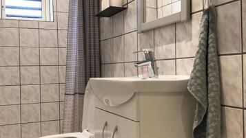 A bathroom with a toilet, a sink, a mirror, and a shower curtain.