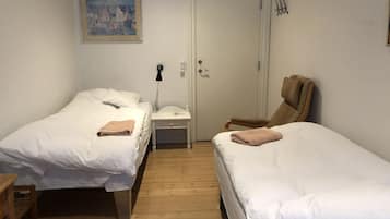 Una habitación con dos camas, una mesita, una silla y una puerta.