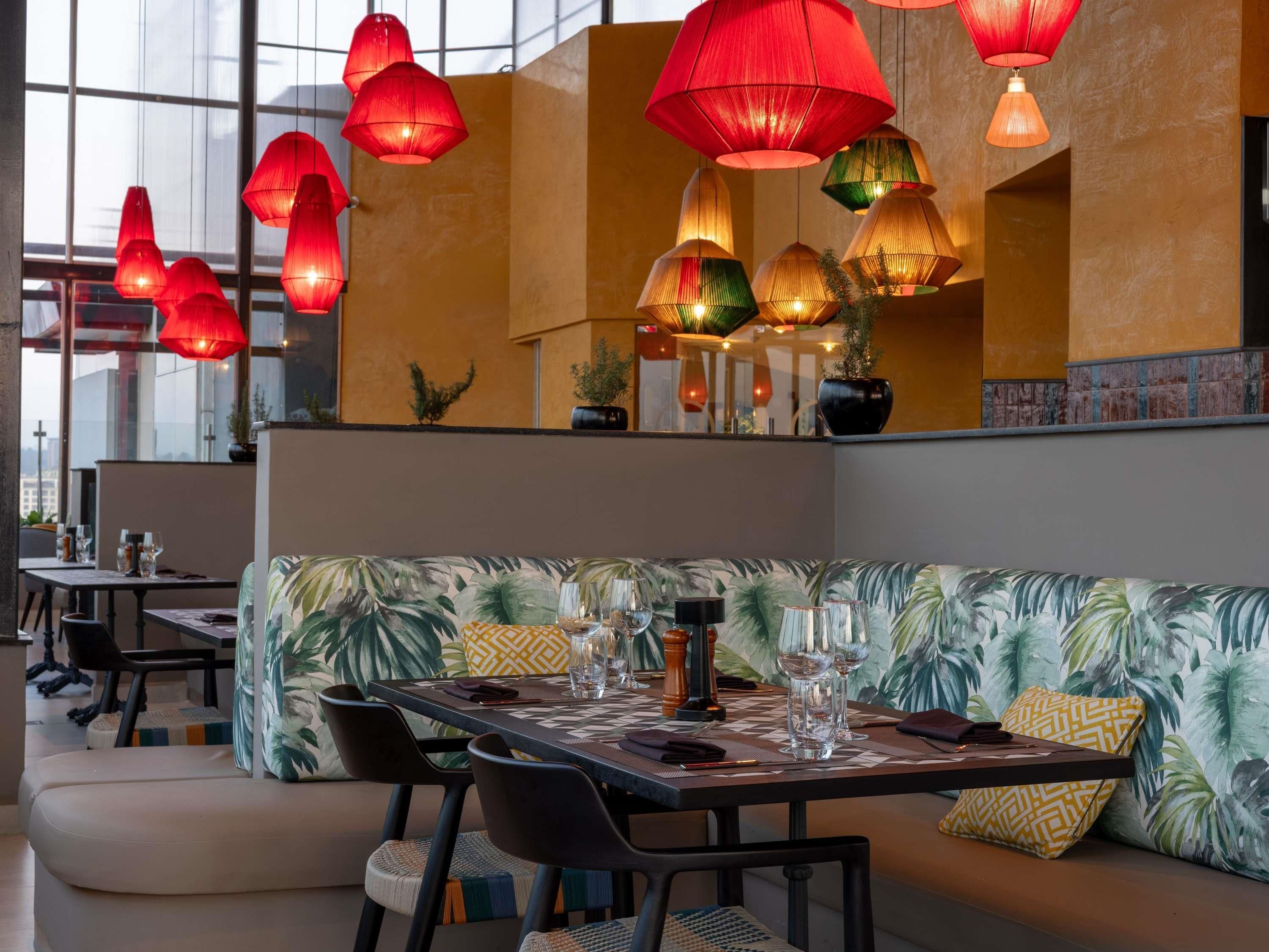 Ein Restaurantinneres mit einer Sitzecke, Tischen und hängenden roten und grünen Lampen.