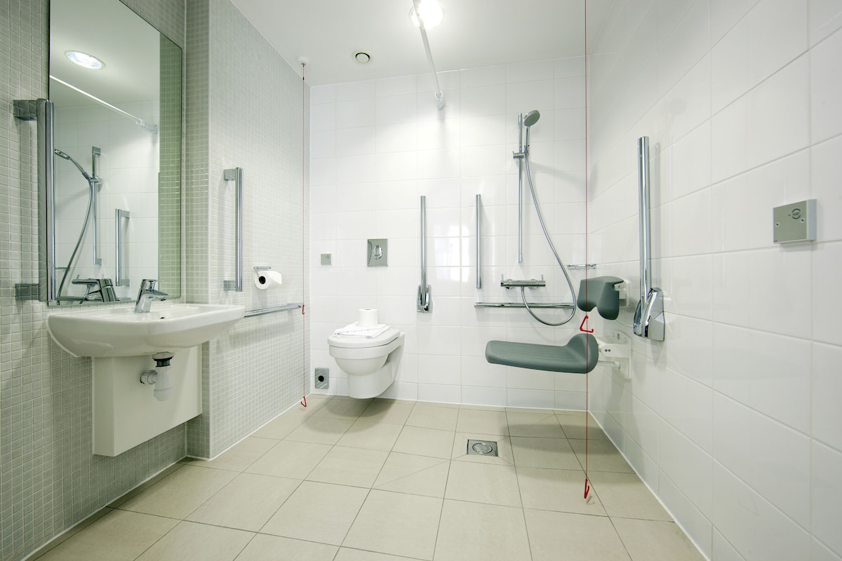 Un baño moderno con lavamanos, inodoro y zona de ducha.