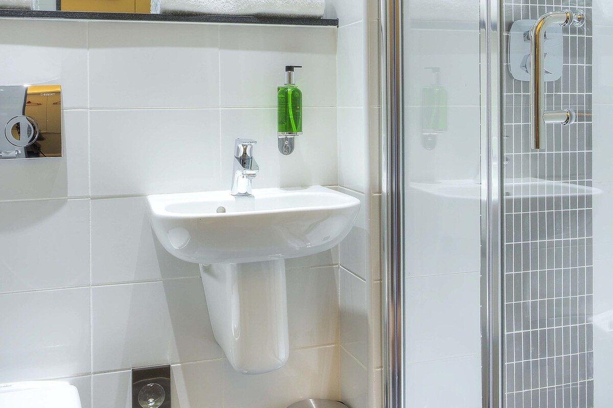 Un baño moderno con ducha de vidrio, lavabo blanco y retrete.