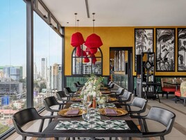 Un comedor con vistas a la ciudad, muebles modernos y obras de arte tropicales.