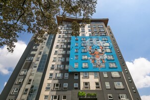 Un edificio de gran altura con un llamativo mural azul en una de sus fachadas y un letrero de "ibis styles" en la planta baja.