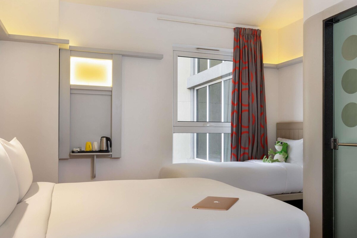 Een hotelkamer met een bed, een bureau, een raam met gordijnen en een deur met ronde patronen.