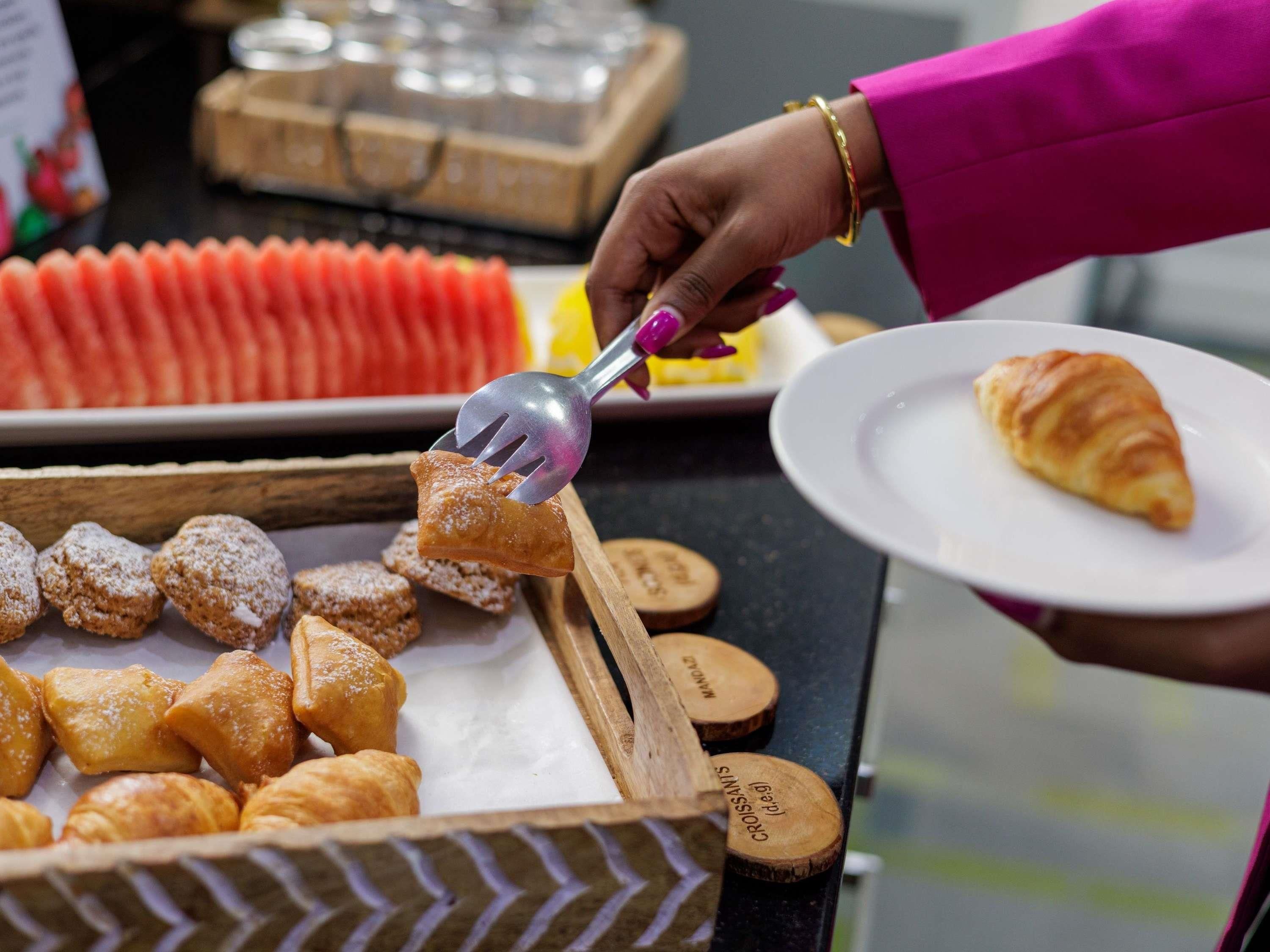 A buffet with various pastries and a croissant on a plate.