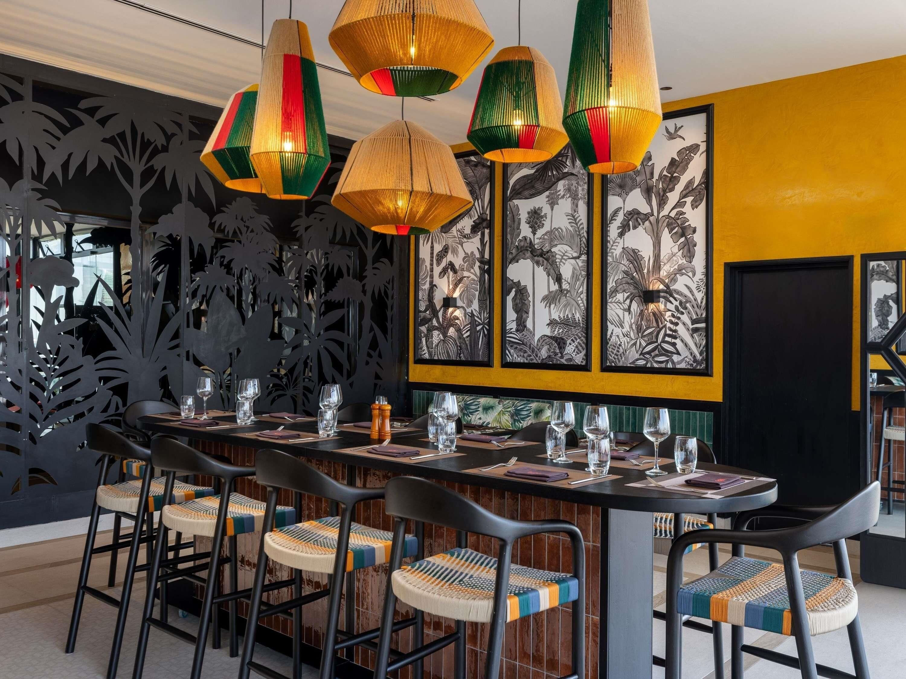 Comedor con una mesa larga, varias sillas y lámparas colgantes.