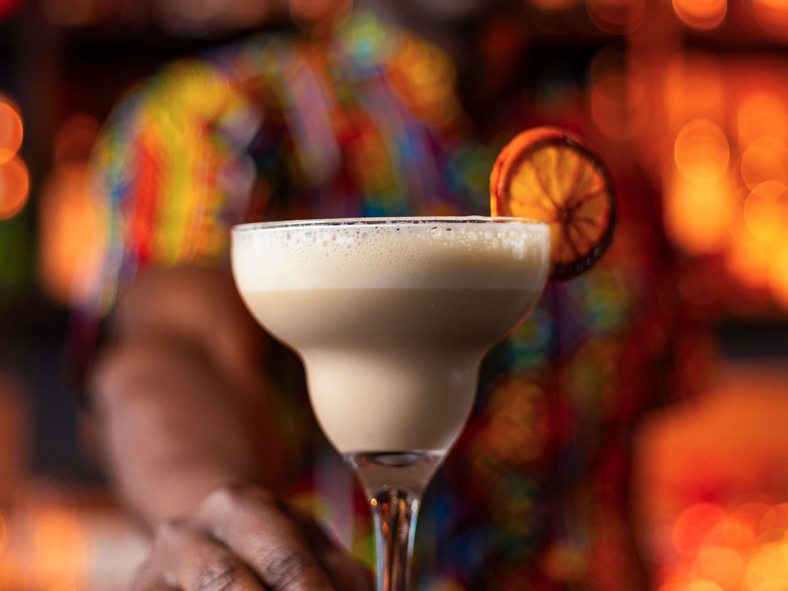 A cocktail in a martini glass with a slice of orange garnish.
