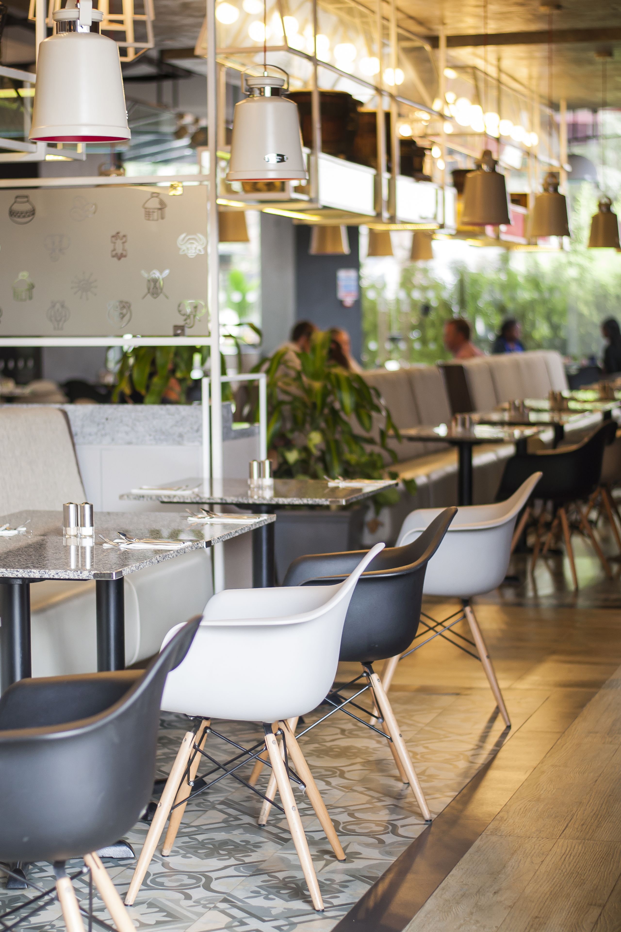 A modern restaurant interior with high tables, chairs, and pendant lighting.