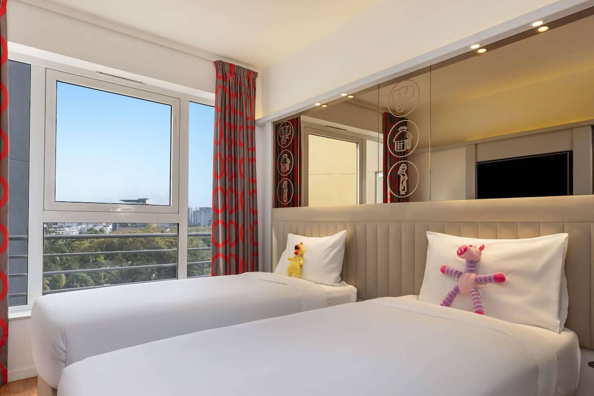 Een hotelkamer met twee bedden, een groot raam en uitzicht op de stad.