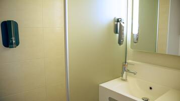 Un baño con un lavamanos blanco, un espejo y un dispensador de toallas.