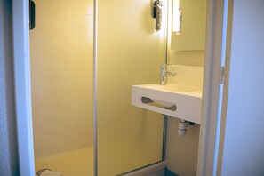 A bathroom with a white sink, a mirror, and a shower enclosure. - B&B HOTEL Metz Est Technopole Pôle Santé (Peltre)