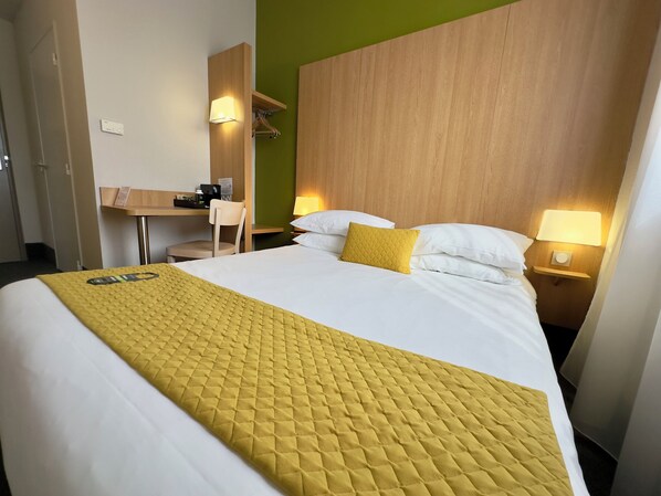 A hotel room with a bed, a desk, a chair, and a nightstand with a lamp. - B&B HOTEL Metz Est Technopole Pôle Santé (Peltre)